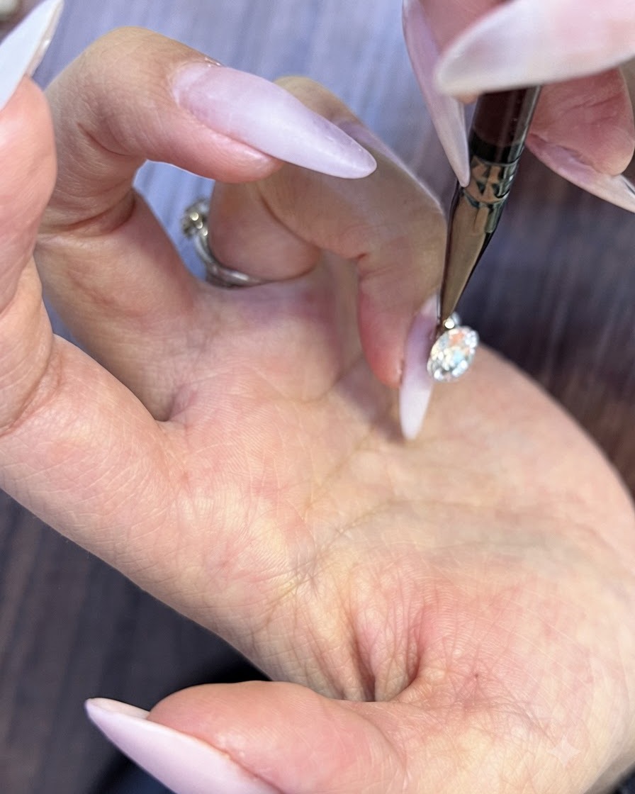 Un outil de détail fin plaçant des micro-strass ronds dans les minuscules espaces sous un grand cristal dongle.