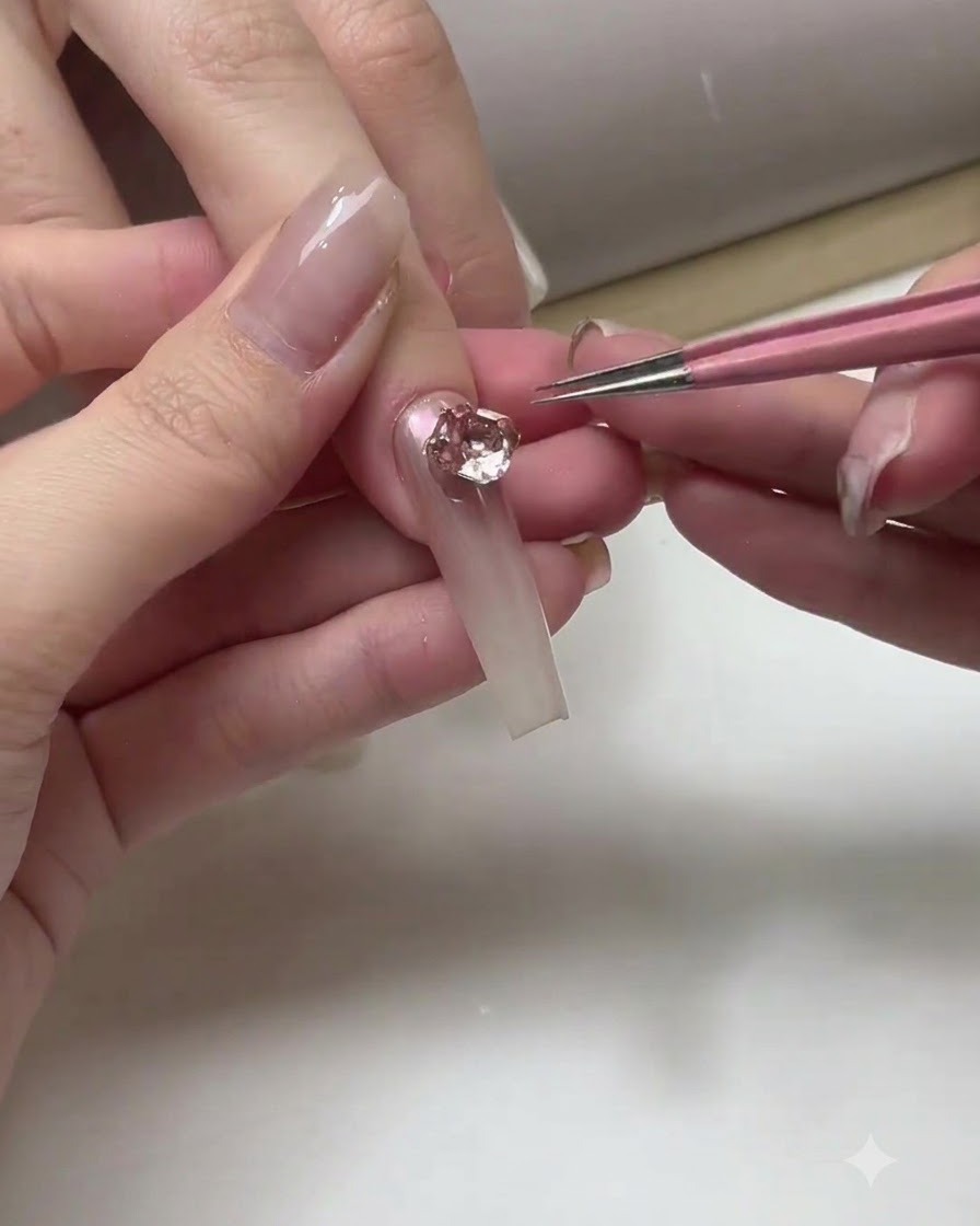 Une prothésiste ongulaire appliquant une couche de finition transparente sur la surface dongles ombrés terminés.