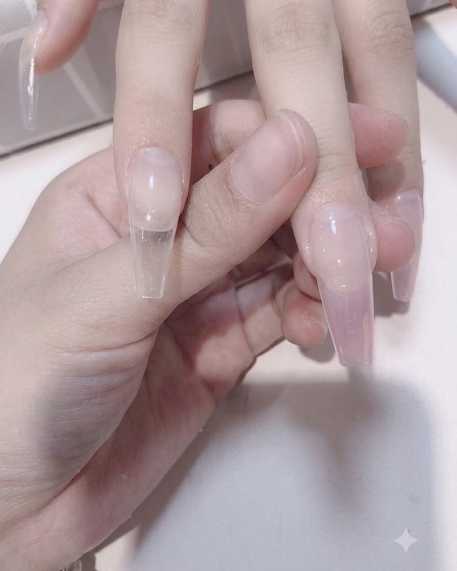 Un pinceau à ongle estompant du gel rose transparent vers le bas sur une extension dongle translucide pour former un effet dégradé.