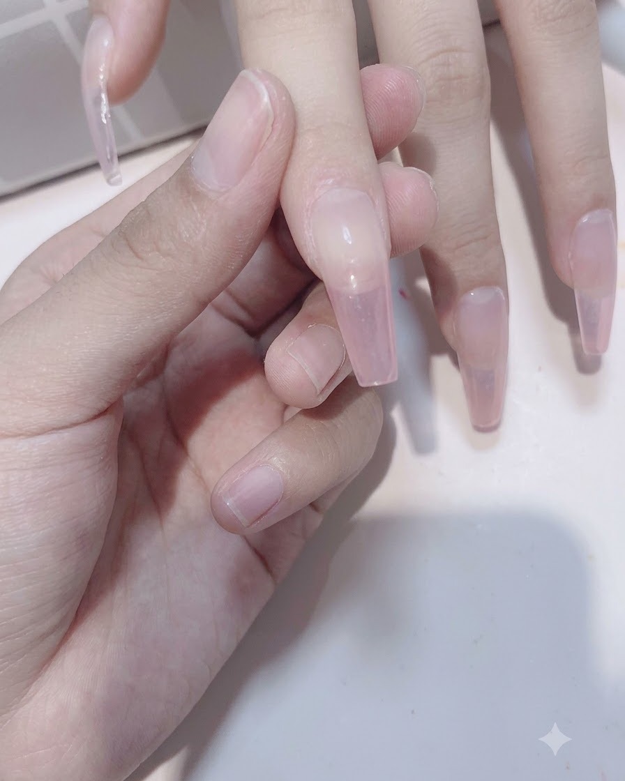 Une vue rapprochée de doigts montrant la deuxième application de gel rose transparent renforçant la profondeur du dégradé.