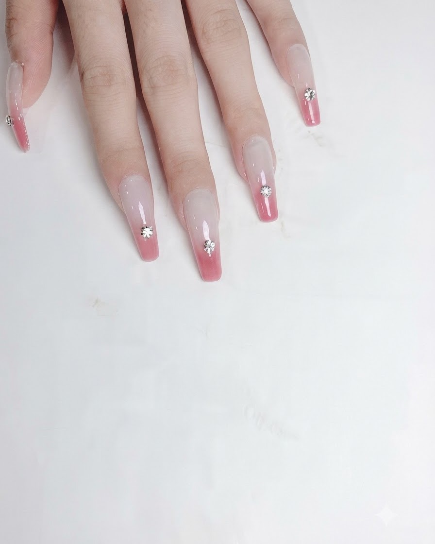 Un outil de précision appliquant une goutte de gel adhésif transparent épais dans la poche creusée sur un ongle.