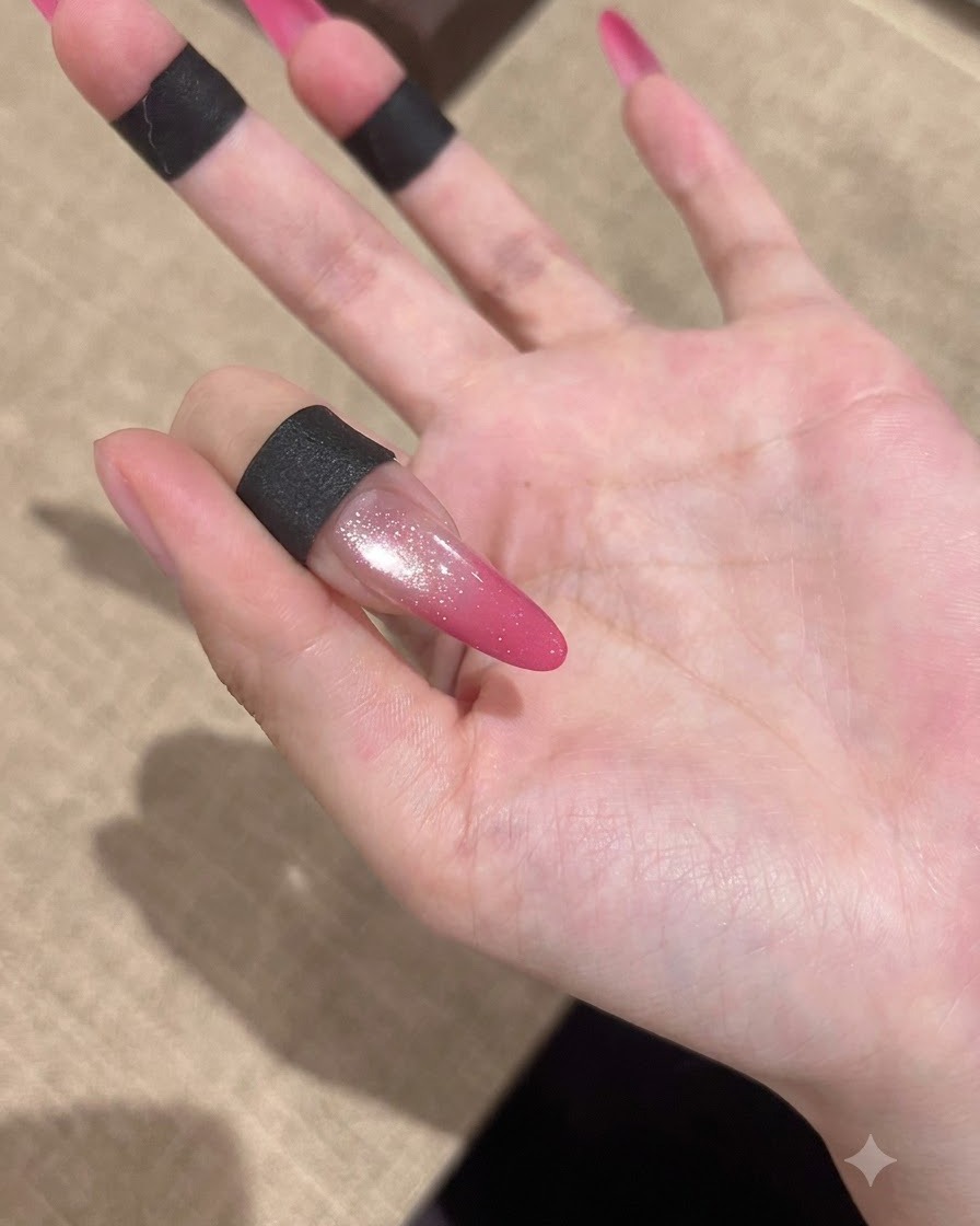 Un ongle rose en dégradé effet œil-de-chat terminé présentant une finition ultra-brillante sur fond doux.