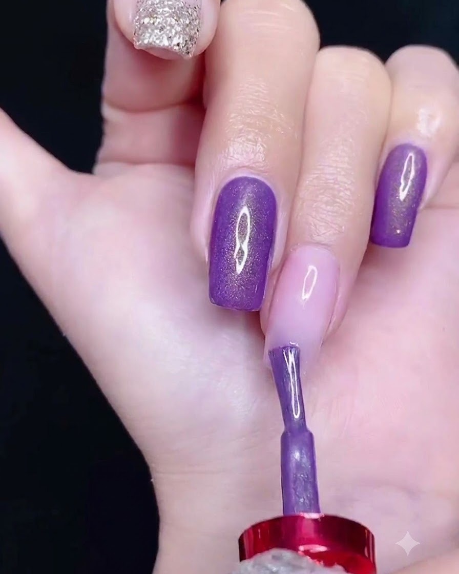 Un pinceau appliquant du vernis semi-permanent violet sur la partie supérieure dun ongle.
