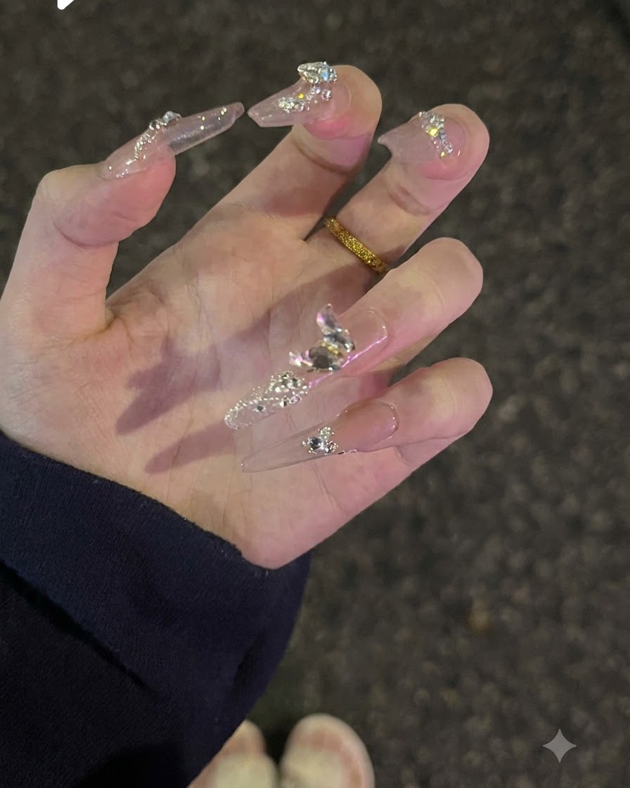 Une main tournée vers le haut pour présenter les paillettes de surface et les cristaux de diamant étincelants sur des ongles nudes.