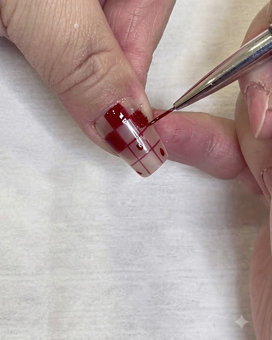 Gros plan détaillé dun pinceau de nail art fin appliquant précisément du vernis gel rouge sur la bordure dun motif damier sur un ongle.