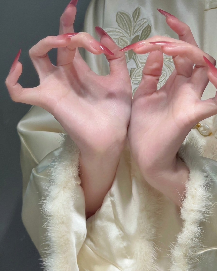 Gros plan de doigts repliés montrant de longs ongles stiletto avec une transition fluide dune base diaphane vers des pointes rouges.
