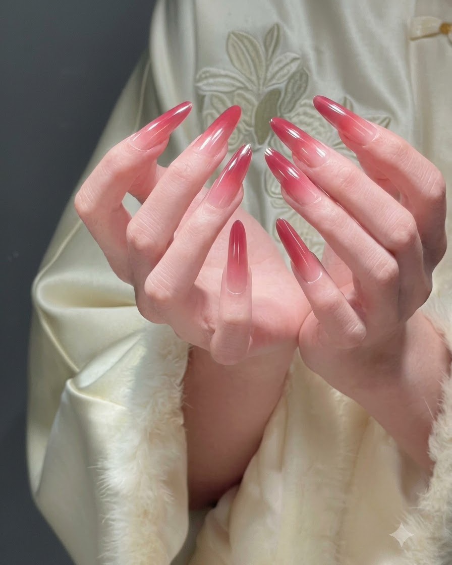 Deux mains jointes présentant tous les doigts pour afficher une manucure ombré rouge festive complète.