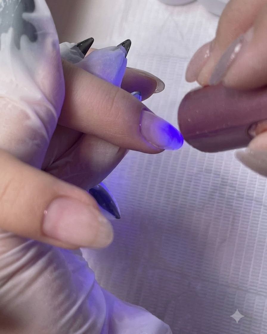 Une mini lampe UV/LED portable catalysant la couche de gel de base sur le doigt dune cliente.