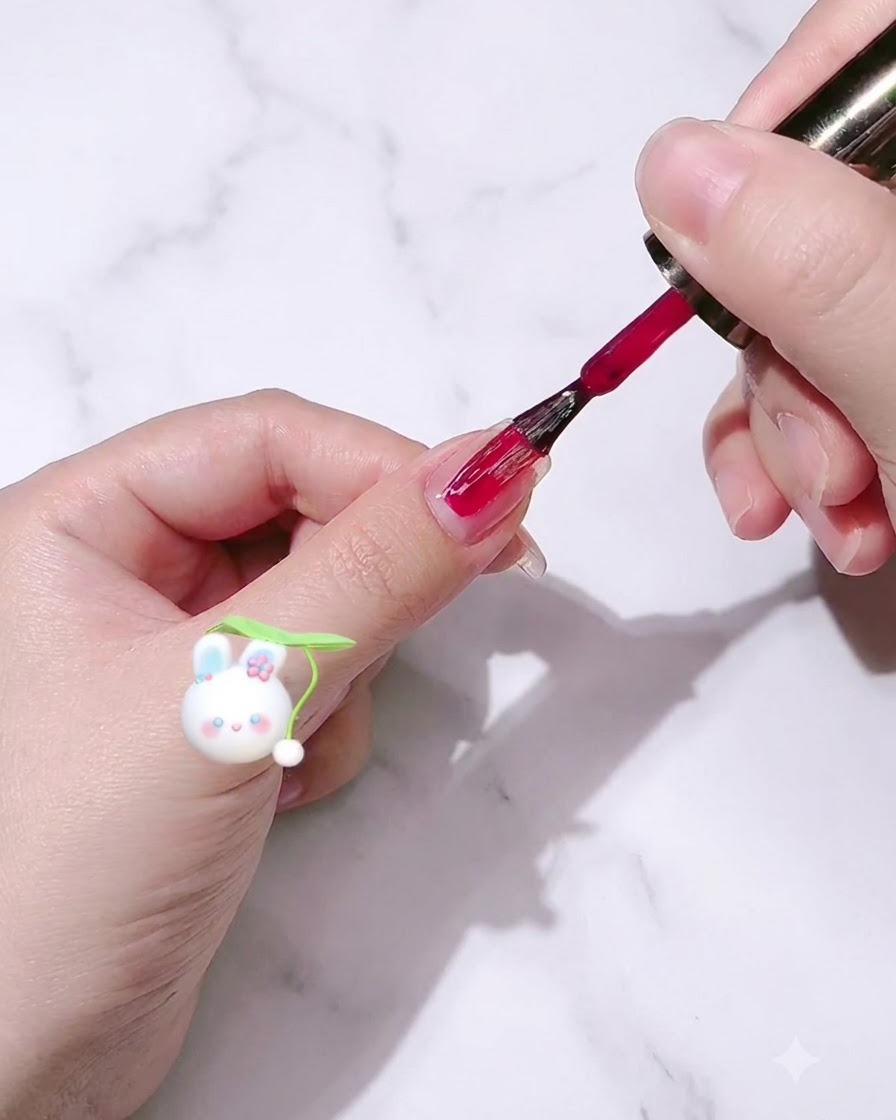 Un pinceau à vernis appliquant du vernis gel rose corail sur un ongle.
