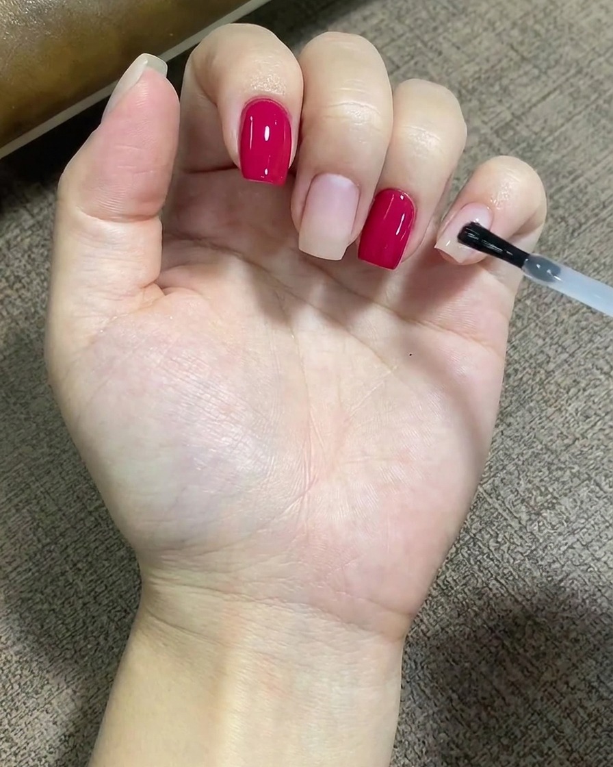 Un pinceau appliquant une couche transparente de base coat uniformément sur la surface dun ongle.