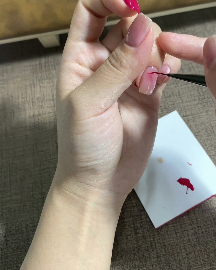 Un pinceau liner fin dessinant un motif détoile magenta détaillé sur une surface dongle préparée.