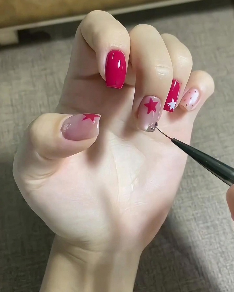 Un outil fin plaçant des cristaux étincelants sur une goutte de gel adhésif sur un ongle décoré.