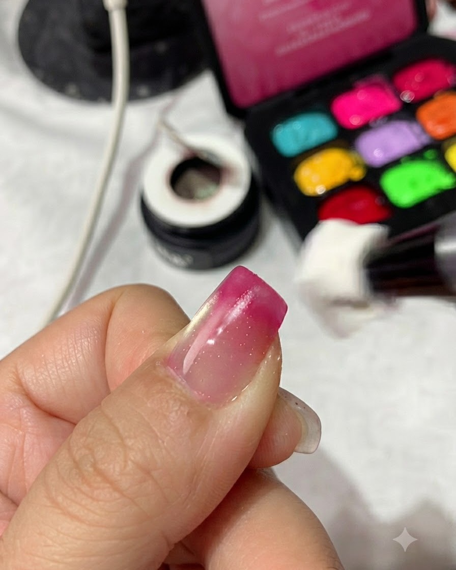 Un applicateur éponge tapotant du vernis gel rouge magenta sur la pointe dun ongle pour intensifier le dégradé.