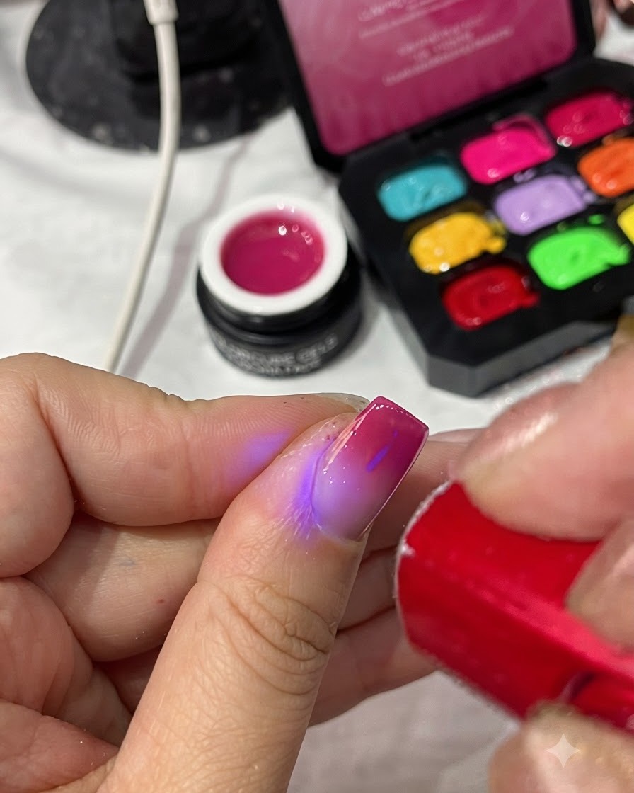 Une lampe UV/LED rouge portable catalysant la couche de finition sur une manucure terminée.