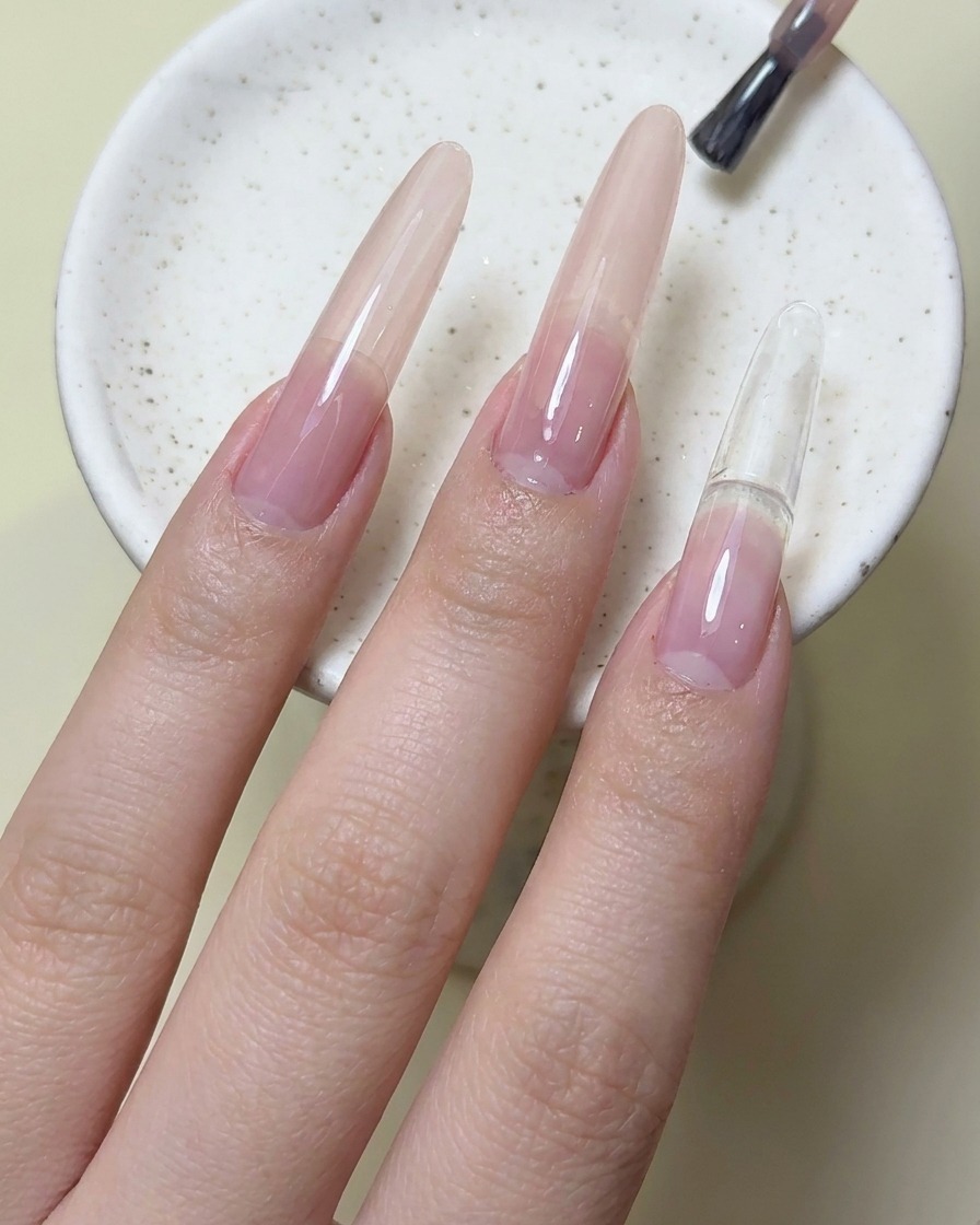 Un pinceau à ongles appliquant du vernis gel rouge magenta sur longle de lindex.