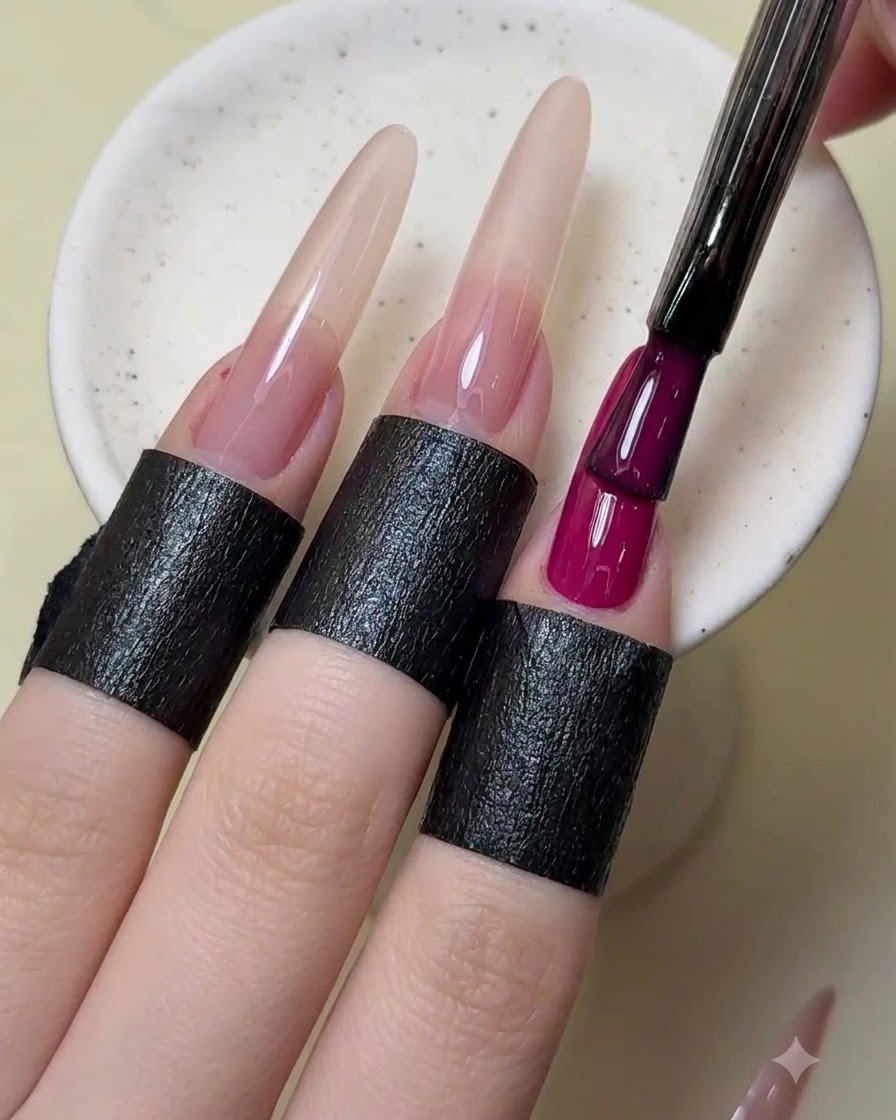 Un pinceau à ongles ajoutant une seconde couche de vernis rouge magenta opaque sur lindex.
