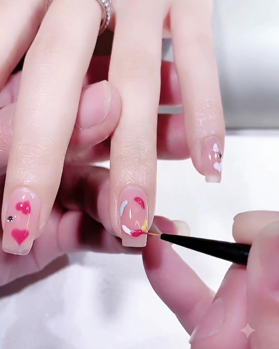 Gros plan dun pinceau de détail fin affinant la section rose pêche vibrante dun design danneau en gel multicolore sur un ongle.