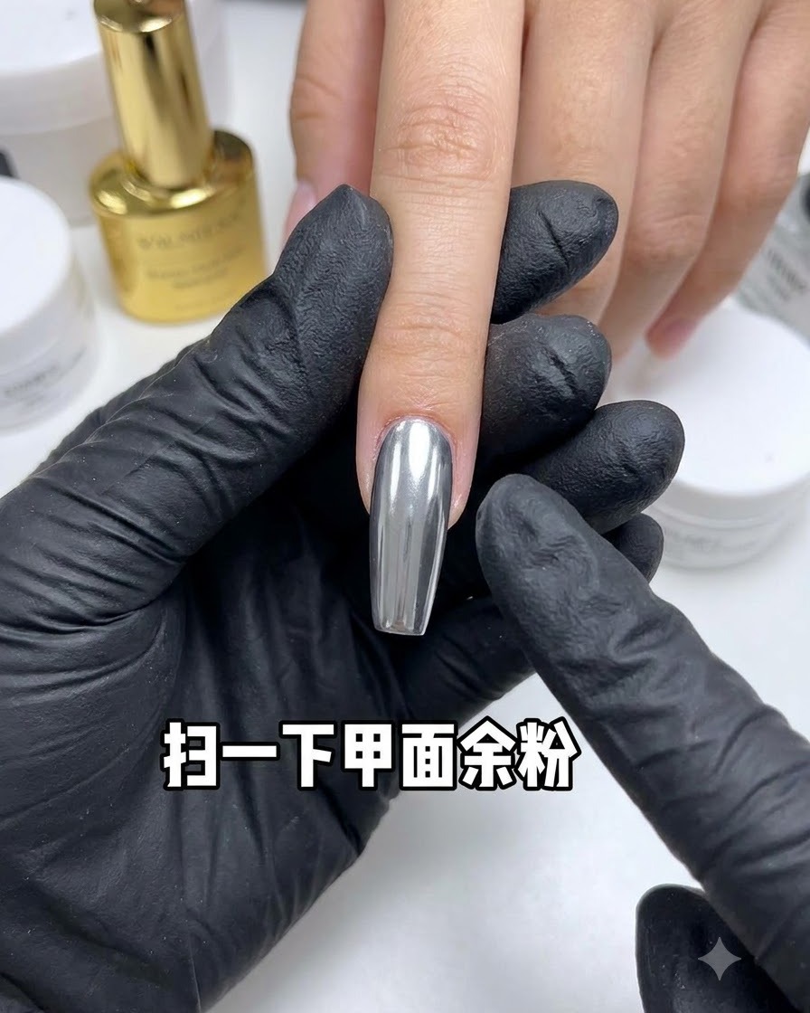 Un pinceau dépoussiérant balayant lexcès de poudre dun ongle chromé réfléchissant.