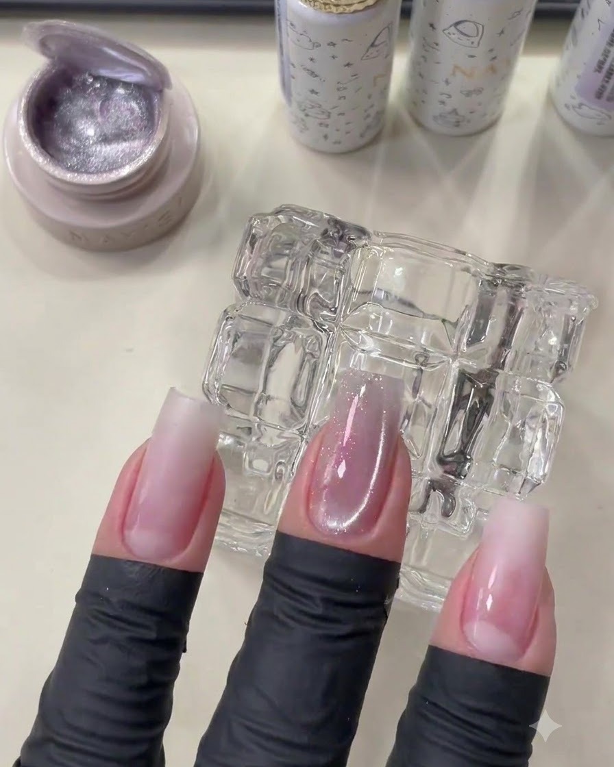 Une main manucurée montrant le gel cat eye catalysé avec un doux scintillement de perle de verre.