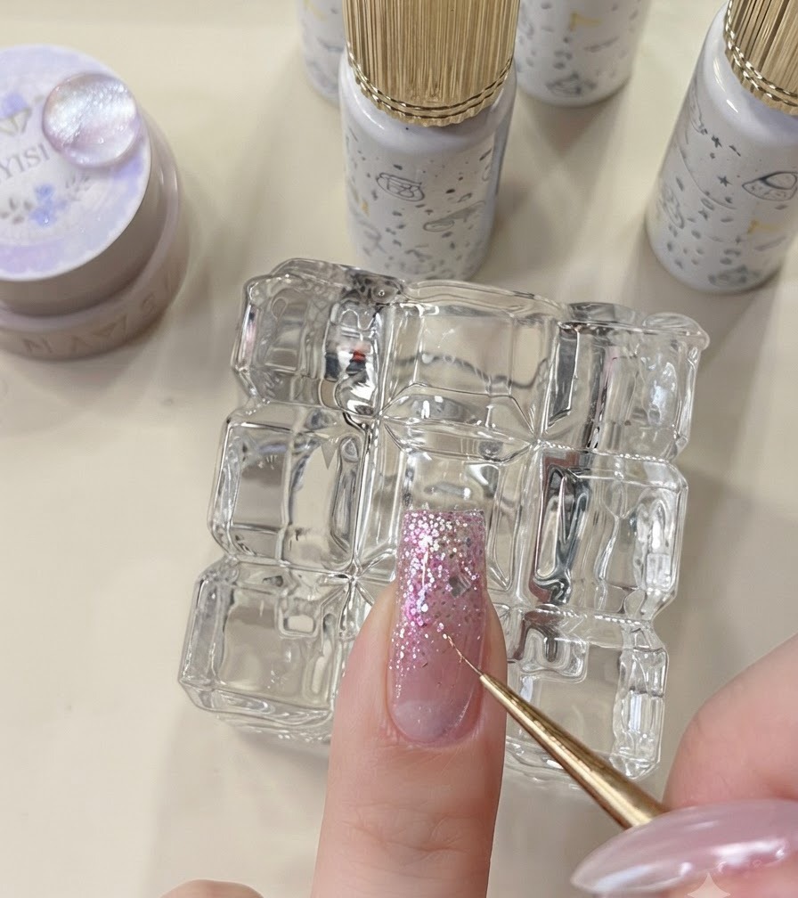 Un outil de détail plaçant des flocons en forme détoile sur un ongle pailleté non catalysé.