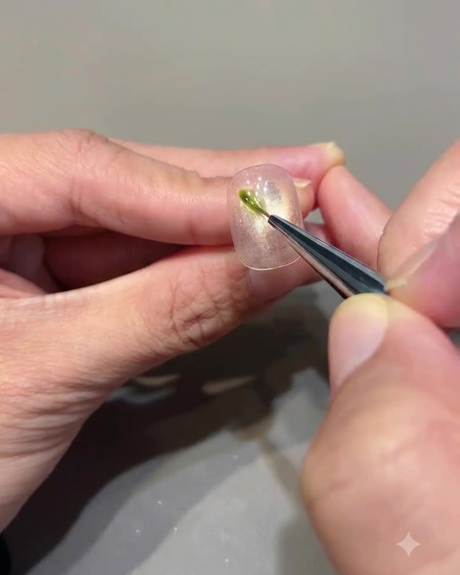 Un pinceau fin appliquant un petit trait vertical de gel vert avocat sur un ongle cat eye.