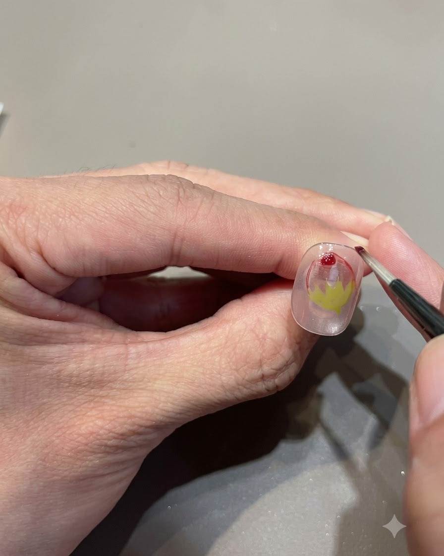 Plan rapproché dun pinceau fin ajoutant une goutte de gel glass rouge pour intensifier le dégradé de la fraise.
