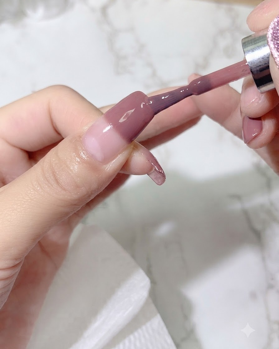 Un pinceau appliquant une deuxième couche de gel coloré sur longle pour intensifier la nuance du dégradé.