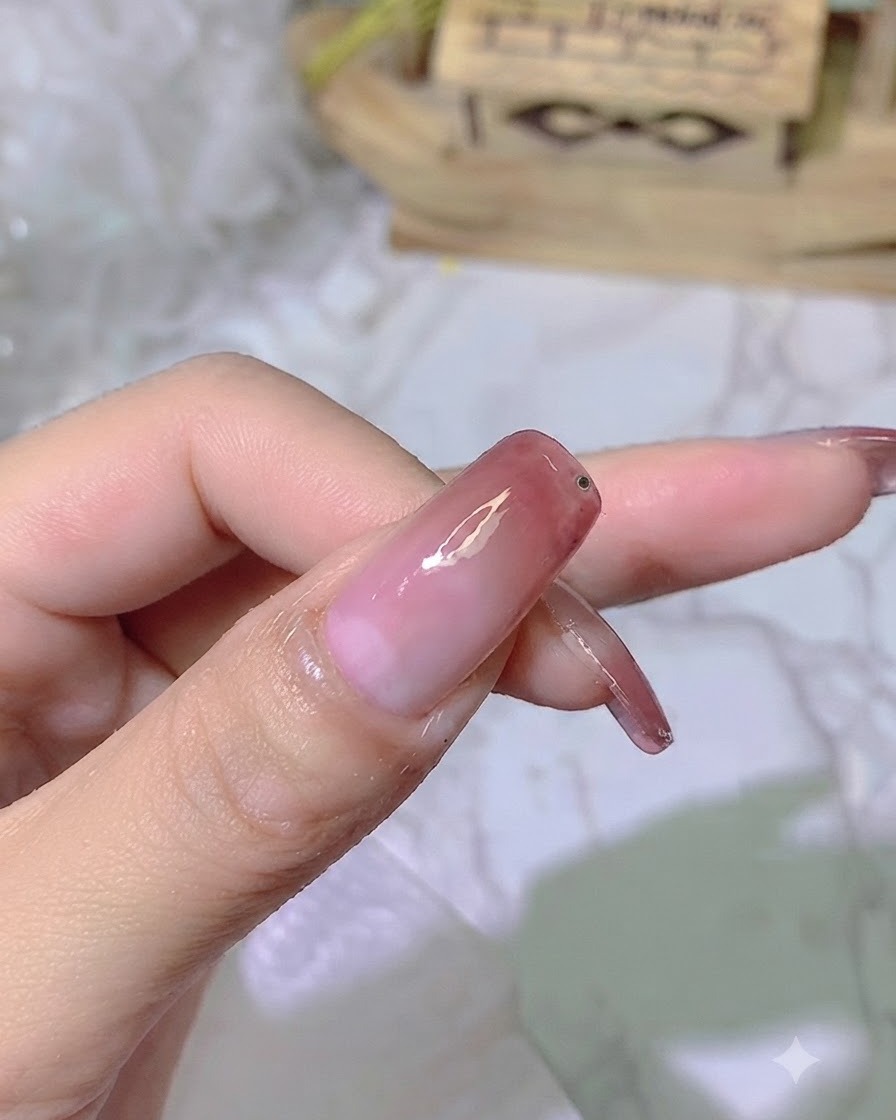 Une minuscule goutte de gel adhésif transparent placée près du bord de longle dégradé fini.