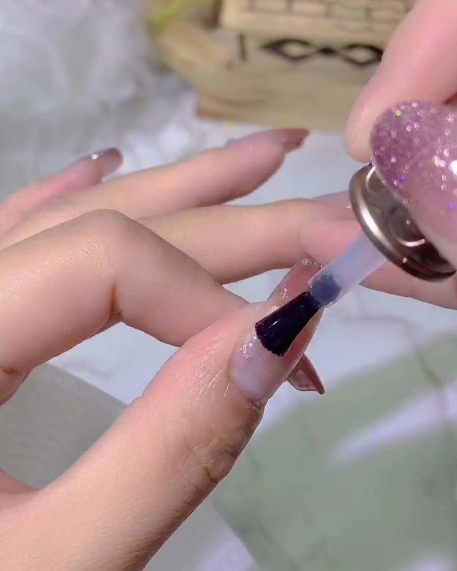 Une main placée sous une lampe à ongles UV ou LED catalysant la couche de top coat.