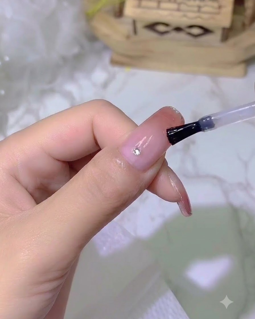 Un minuscule cristal étincelant placé sur un ongle à laide dun outil de précision.