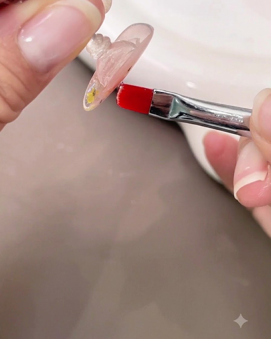 Une main tenant un ongle à lenvers tout en utilisant un petit pinceau pour vérifier lapex du gel de construction transparent auto-égalisant.
