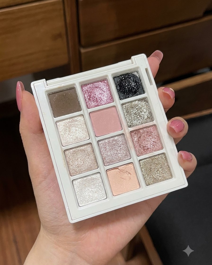 Gros plan sur une main tenant une palette de gels à plusieurs compartiments présentant différentes couleurs pastel et pailletées.