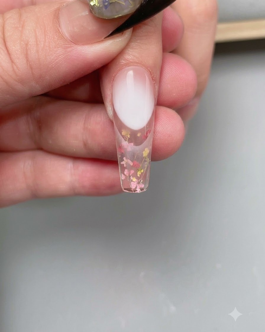 Une pince à épiler positionnant un guide autocollant incurvé pour ongle French sur le bout de longle.