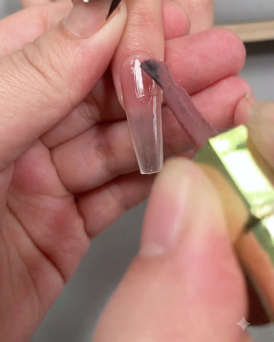 Un pinceau appliquant une couche brillante de top coat diamant sur toute la longueur de longle.