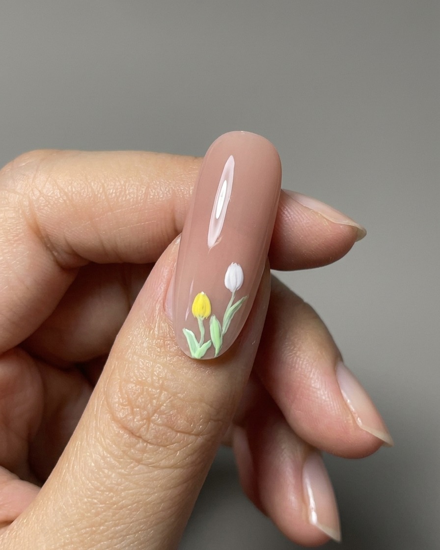 Vue rapprochée de tulipes peintes en 3D achevées sur un ongle nude brillant.