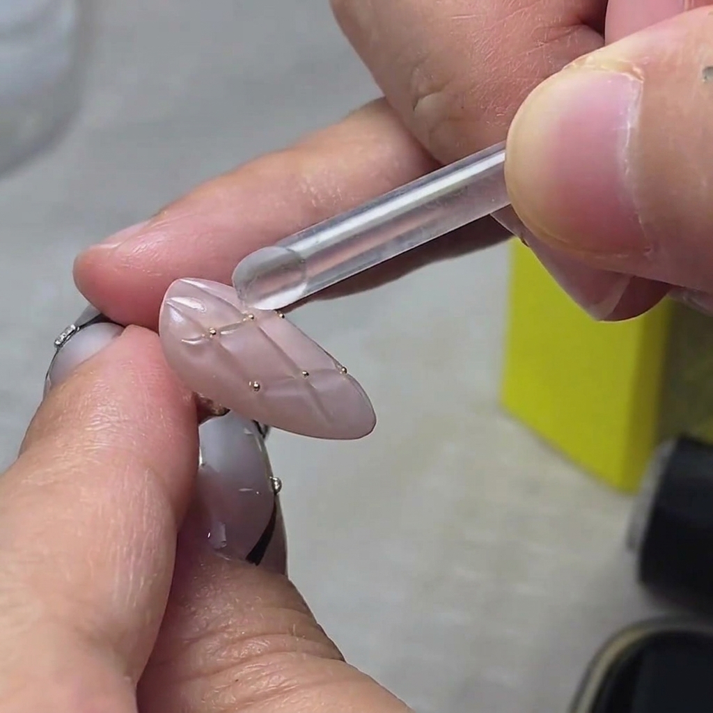 Gros plan de flocons de paillettes dorées appliqués sur le bout dun ongle.