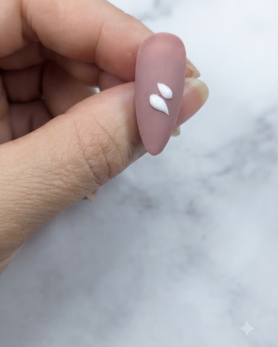 Gros plan dun ongle nude rosé montrant deux traits de pétales blancs distincts appliqués près du centre.