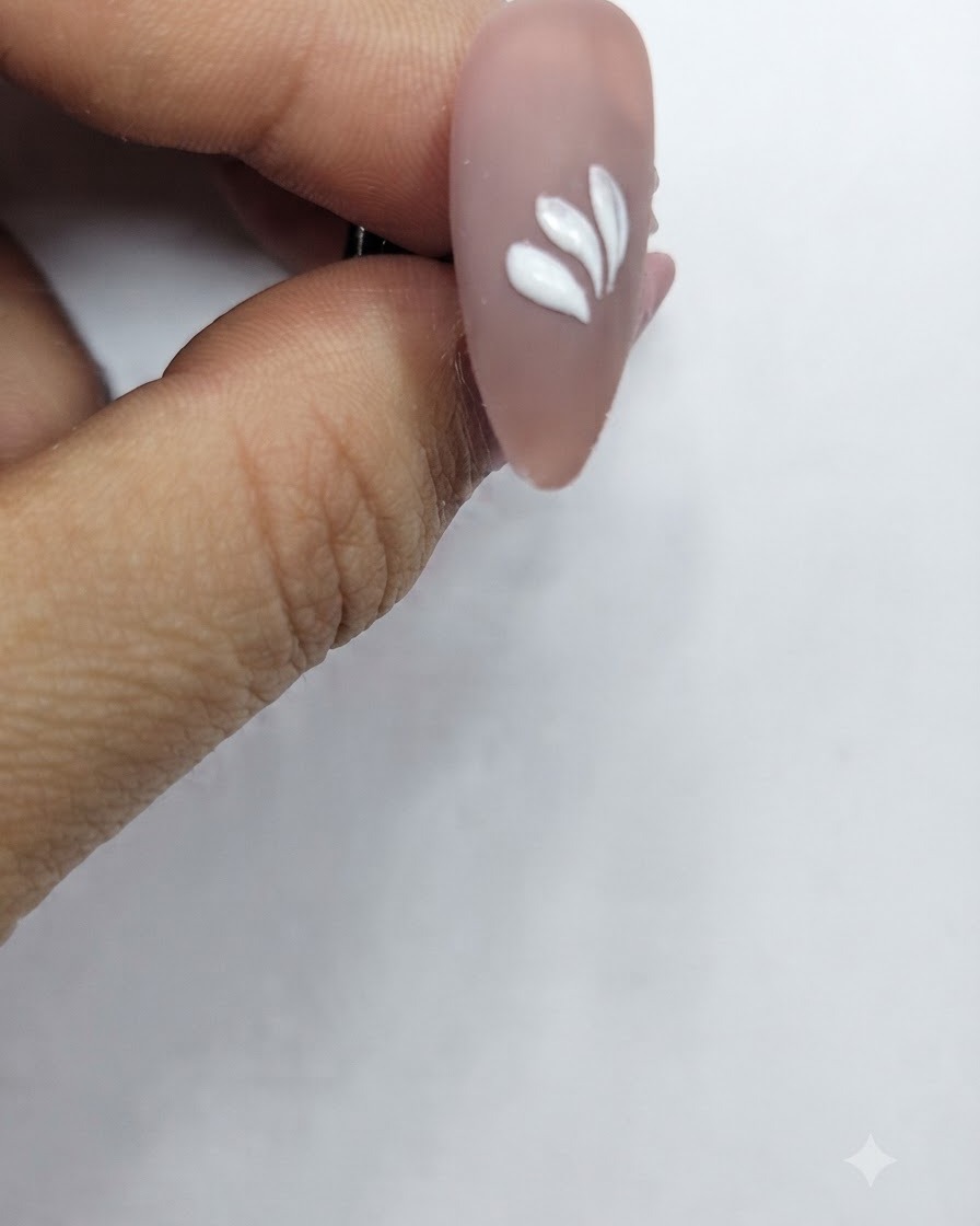 Un ongle avec plusieurs traits de pétales blancs disposés selon un motif circulaire partiel.