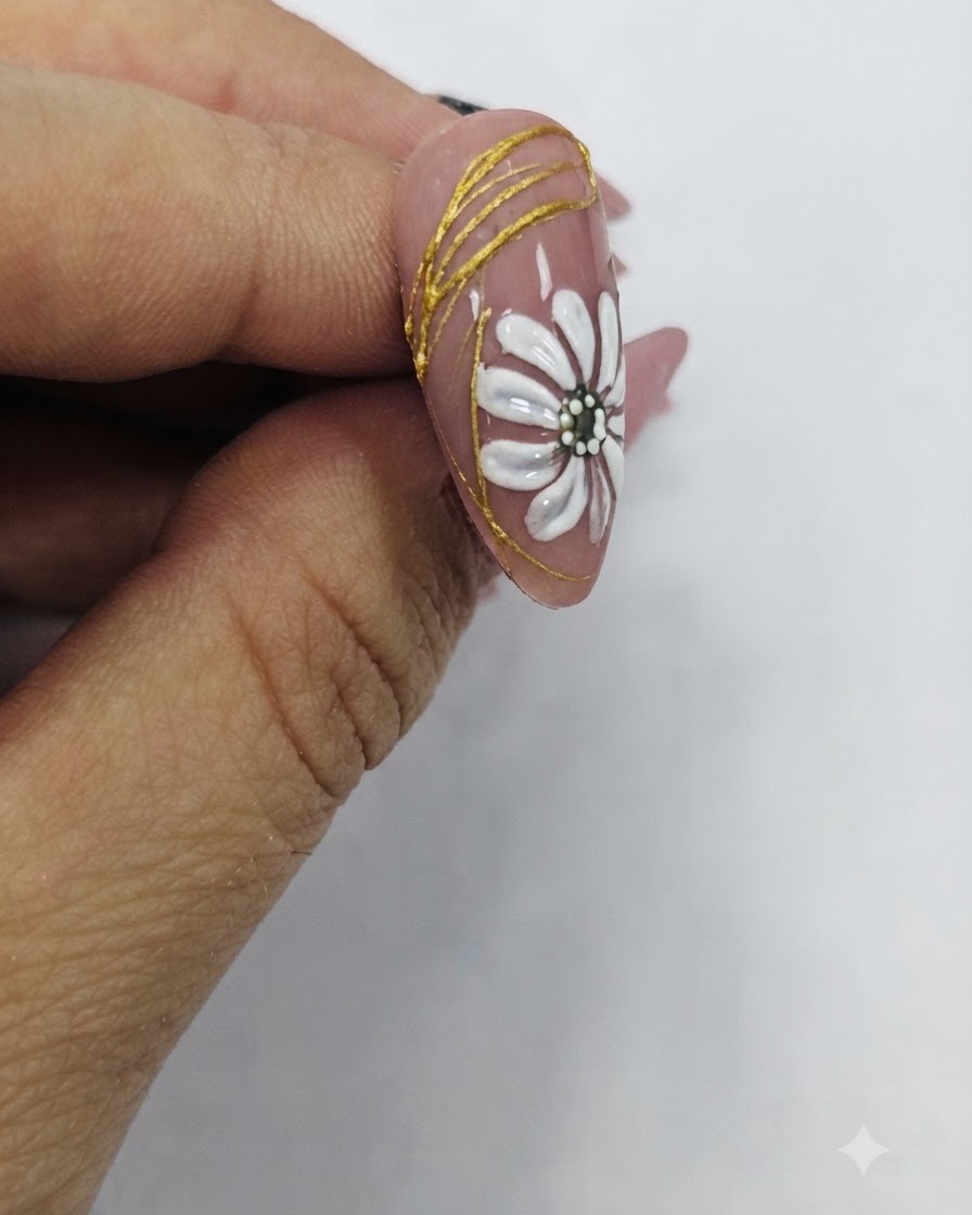 Un pinceau appliquant un top coat transparent brillant sur un design dongle fini mettant en vedette une marguerite blanche et des accents dorés.