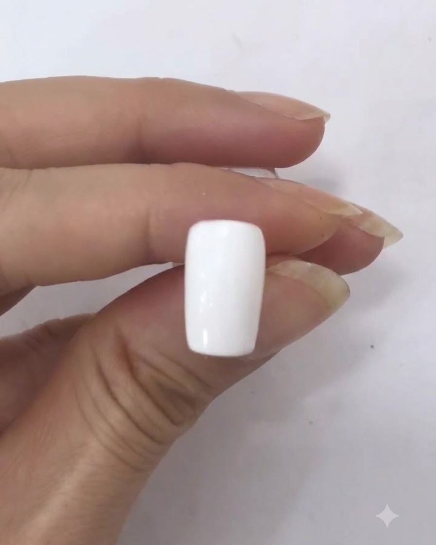 Un unique point rouge foncé reposant au milieu de la surface dun ongle blanc.