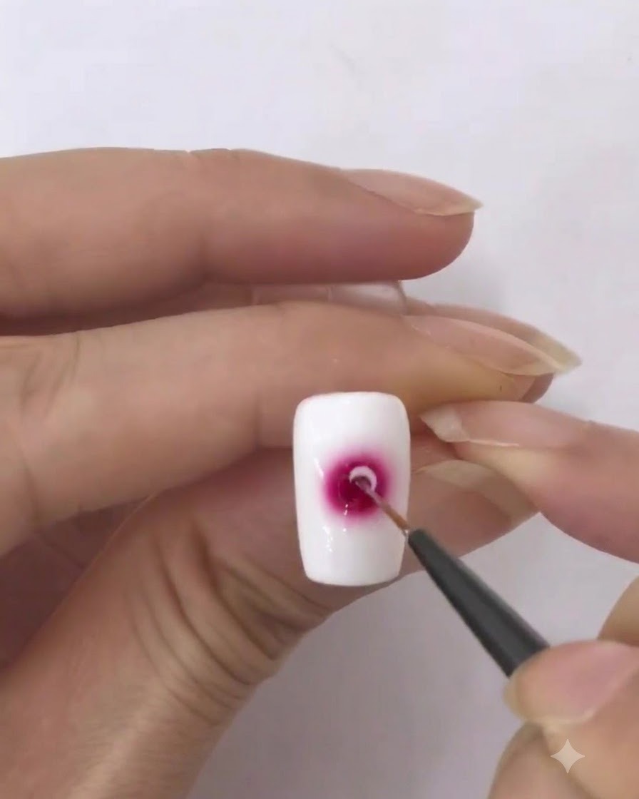 Un pinceau fin chargé dune petite quantité de vernis gel blanc.