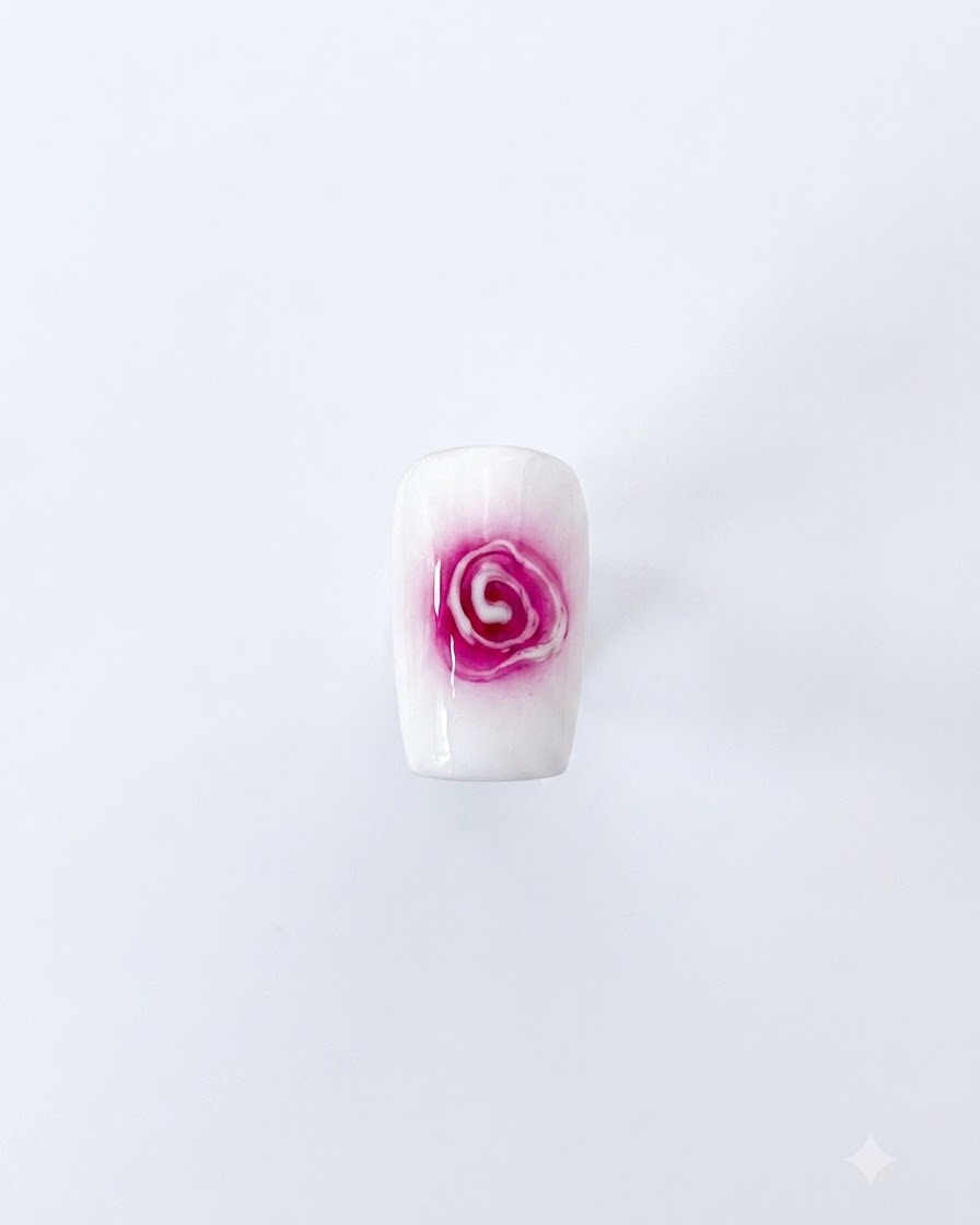 Un nail art de rose épanouie terminé présentant un centre rouge et des pétales blancs doux qui sétendent sur un fond blanc.