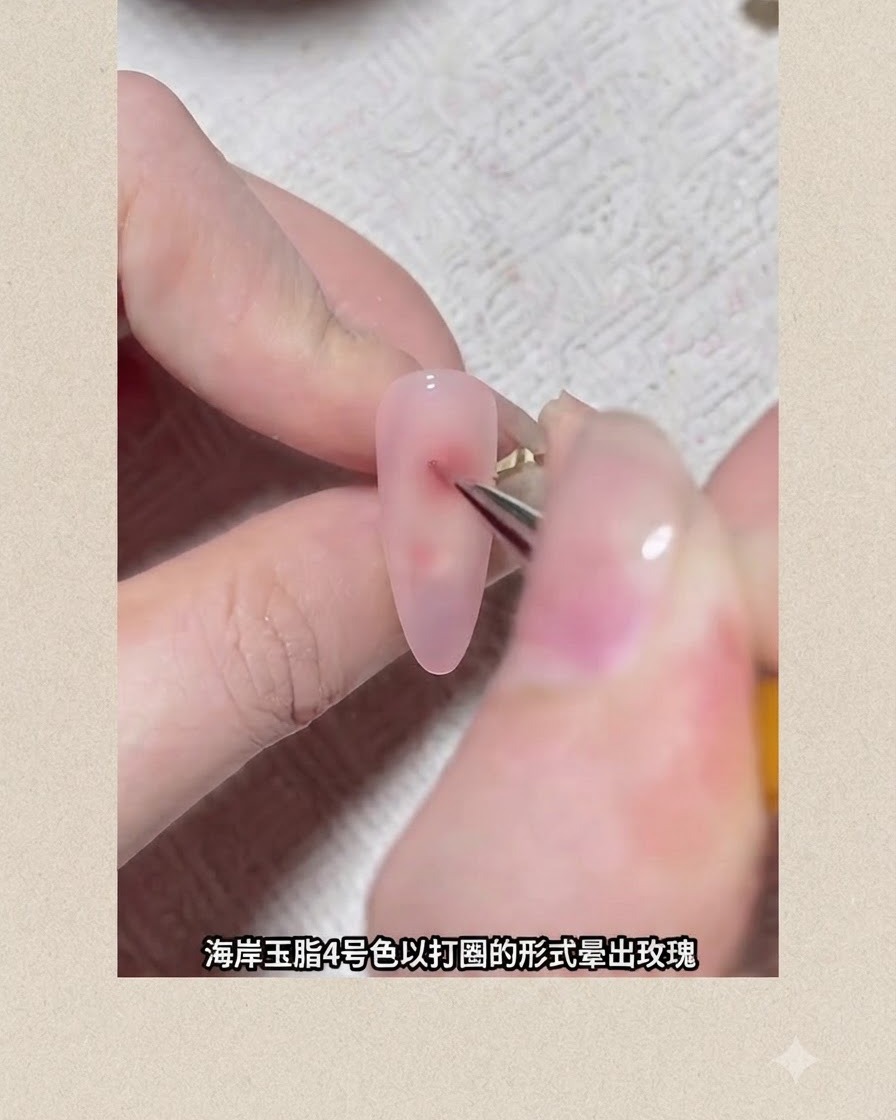 Un pinceau fin de nail art dessinant un point de pigment circulaire rougeâtre sur un ongle enduit de gel rose pour former une fleur blooming.