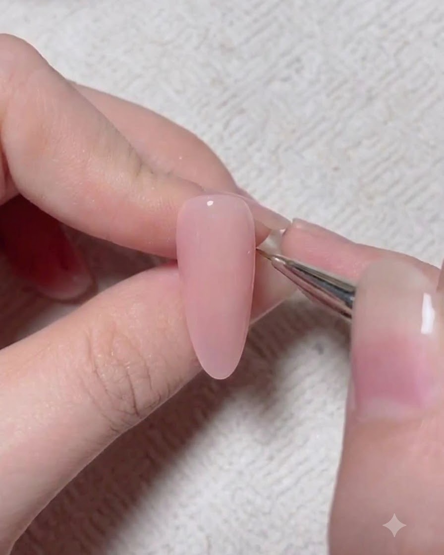 Un pinceau de détail appliquant un pigment daccentuation plus foncé sur la surface dun ongle en gel rose.