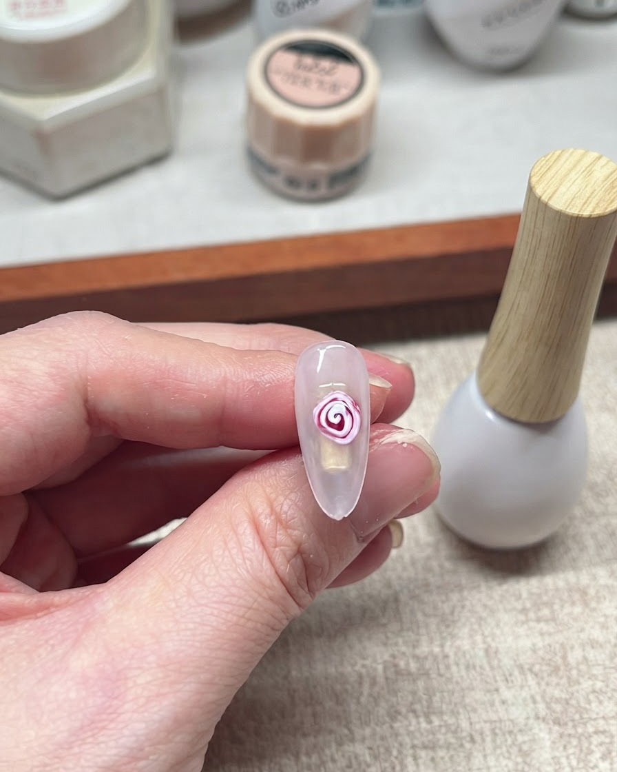 Un design de rose en blooming gel rouge et blanc terminé sur un ongle.