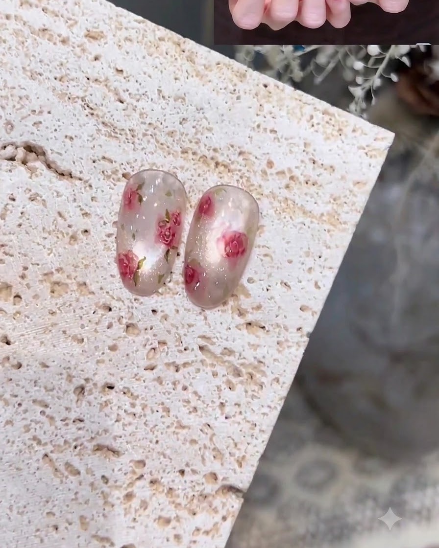 Gros plan dune main utilisant un pinceau fin de détail pour peindre des contours délicats sur un ongle blanc laiteux et translucide.