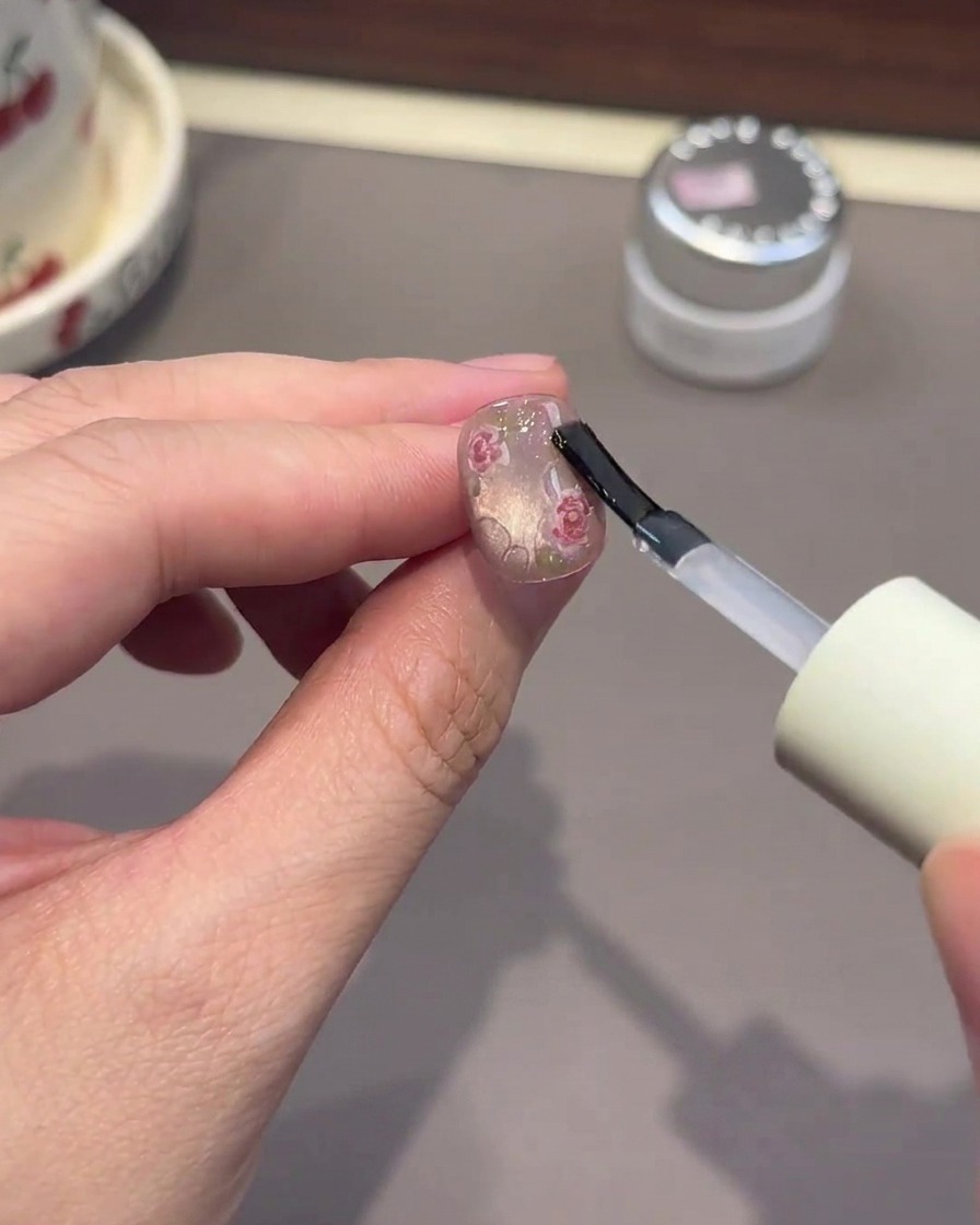 Un pinceau appliquant du gel transparent épais pour former des effets de gouttes deau sur longle.