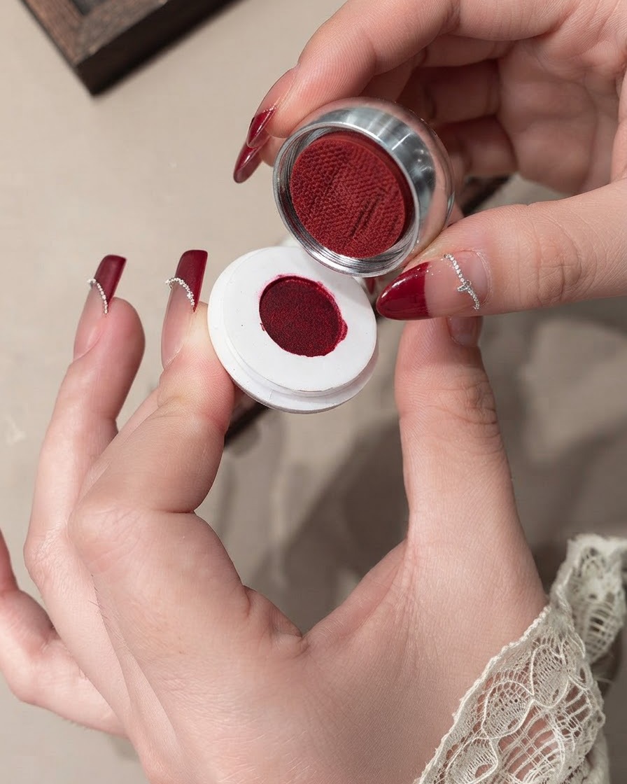 Gros plan dun pinceau lissant du gel velours rouge sur un ongle.