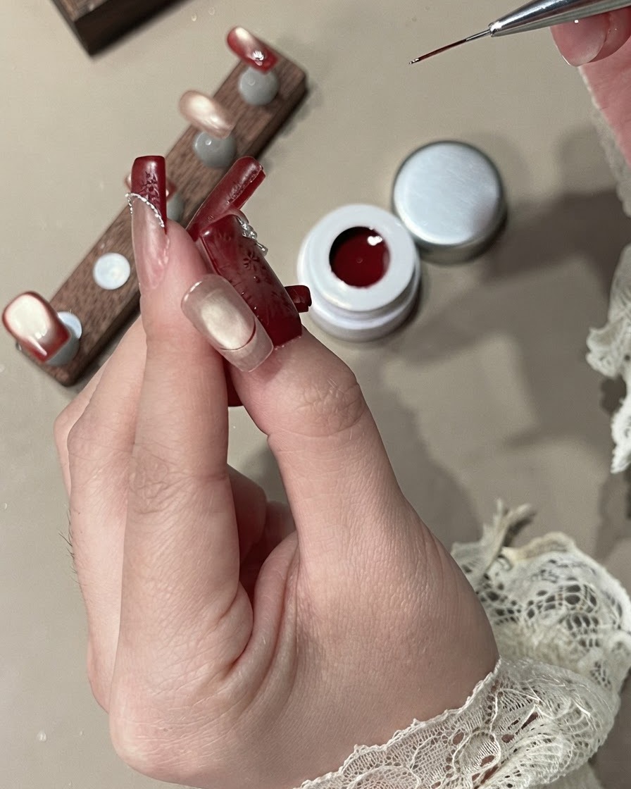 Un pinceau liner remplissant la zone du French tip avec du gel velours rouge opaque.