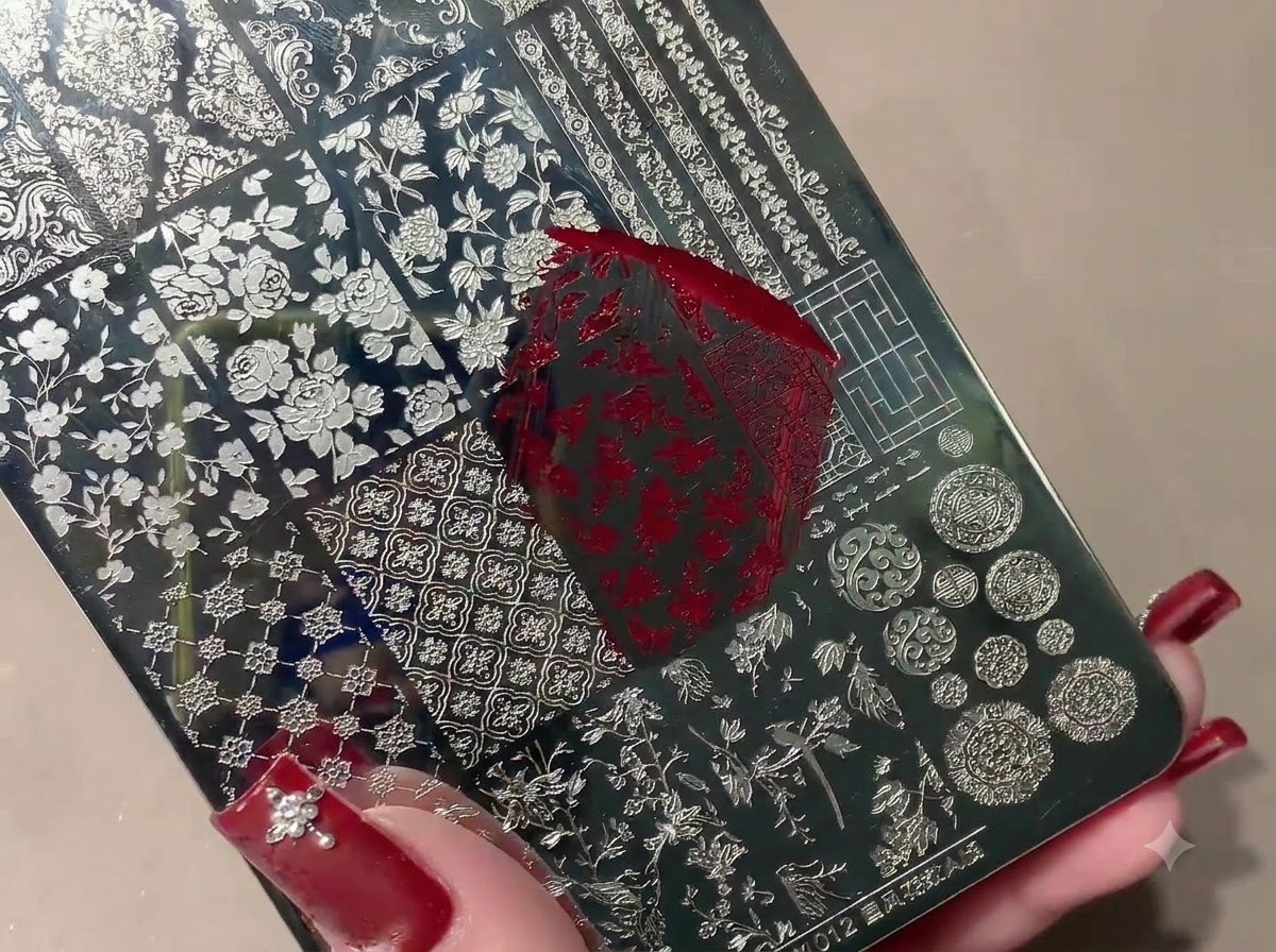 Un tampon en silicone ramassant un motif estampé rouge sur une plaque de stamping métallique.